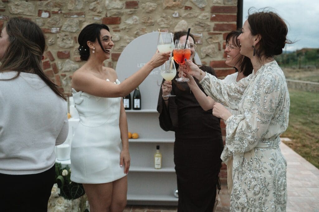 Tien vragen die je moet stellen aan je trouwfotograaf. De bruid en g
haar gasten proosten met Aperol Spritz tijdens de borrel op de bruiloft
