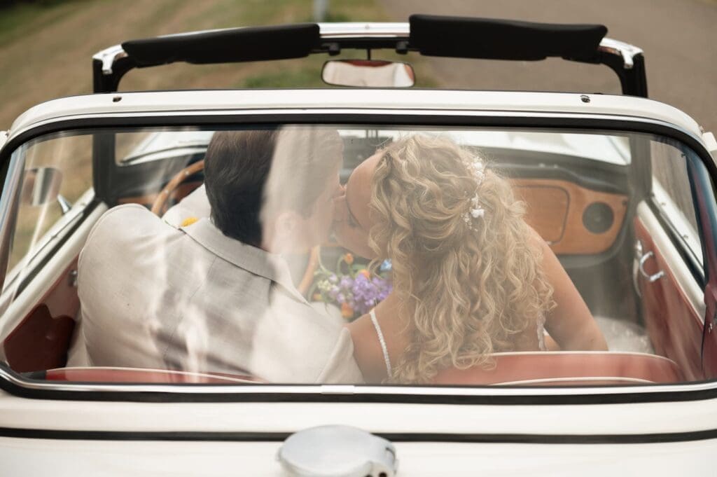 Trouwen bij Landgoed huis Brakel, verliefd bruidspaar in een vintage antieke auto kust elkaar